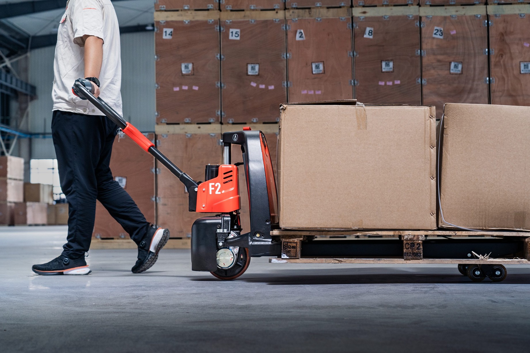 A man pulling a electric pallet truck with heavy load on it.