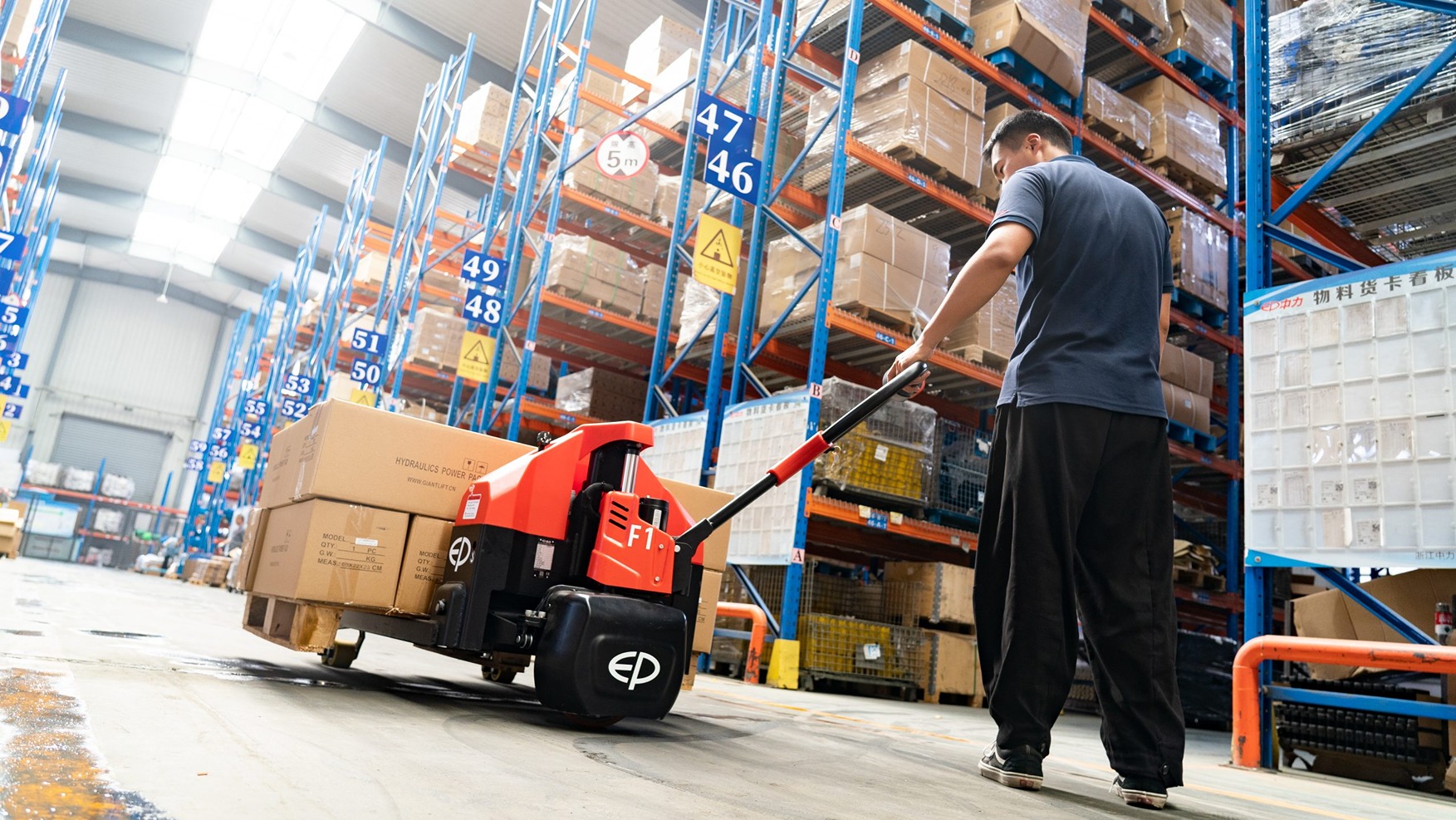 A man using electric pallet truck to load heavy goods.